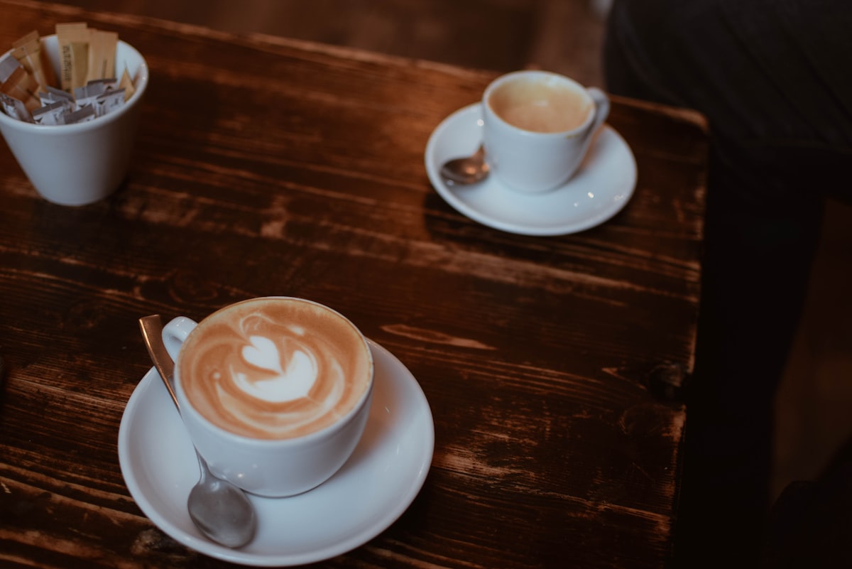 Café Central – White ceramic cup with saucer on brown wooden table