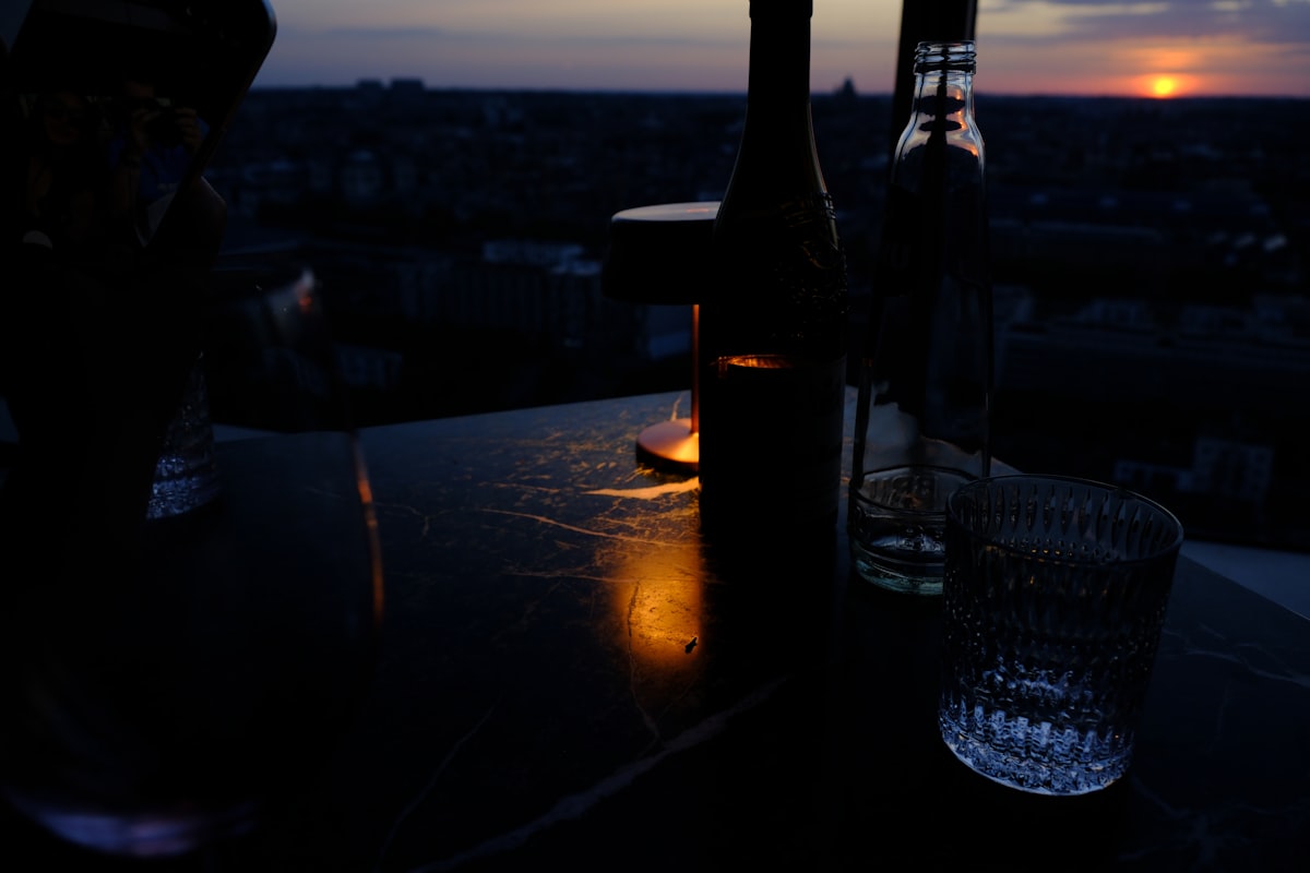 Liquid Diary – A bottle and a glass on a dark table with low light at night