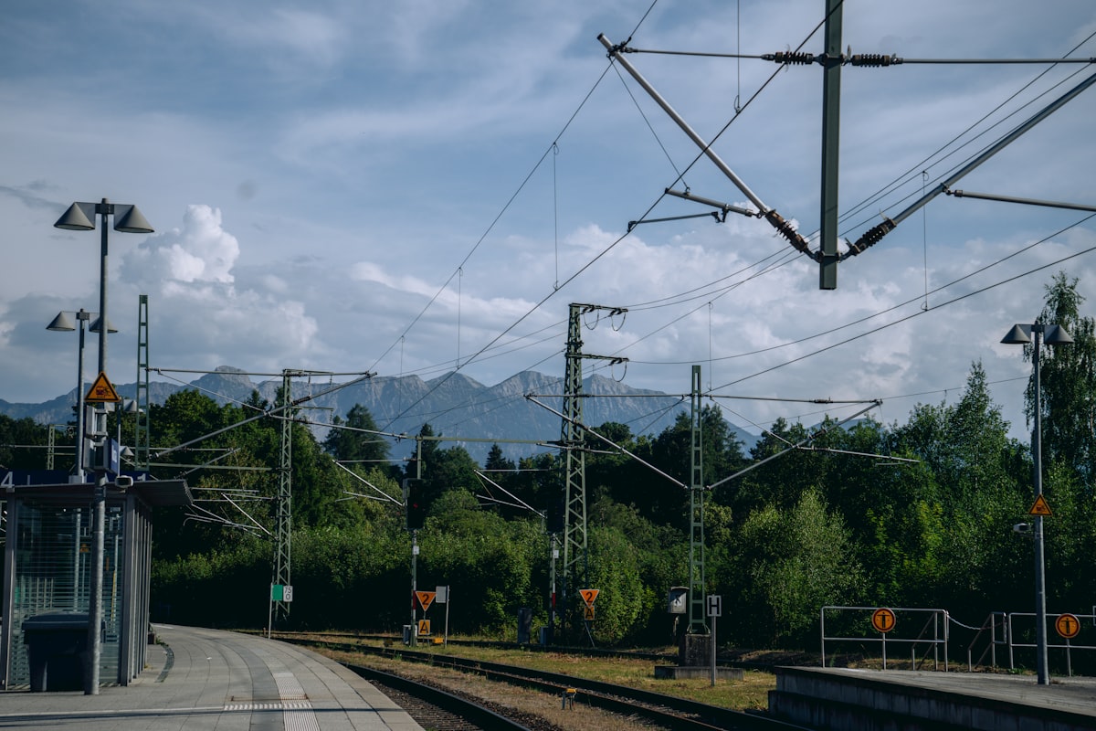 ÖBB Railjet Hauptbahnhof – Train station with tracks, power lines, and mountains