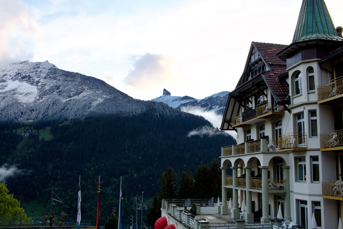 Pension Stoi – Ornate hotel building with snow-capped mountains and forests in background